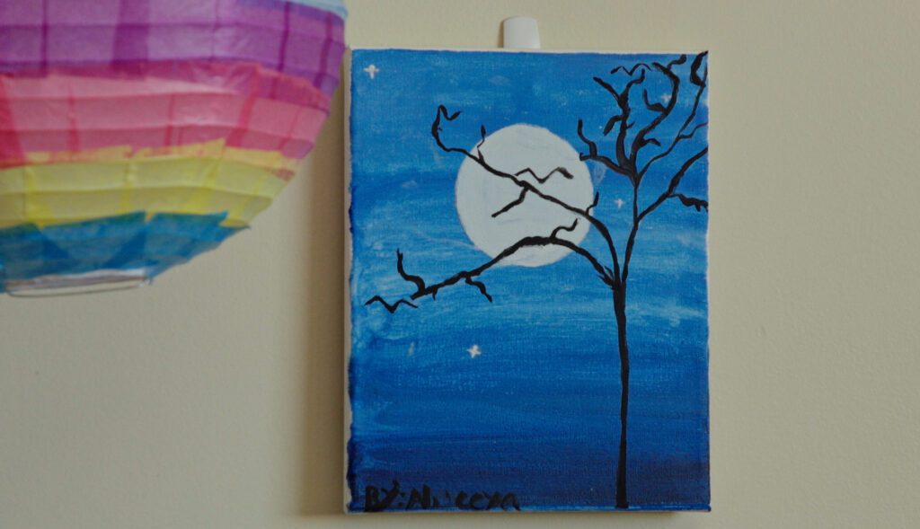 An image of a tree in front of a moon that a patient painted on canvas.