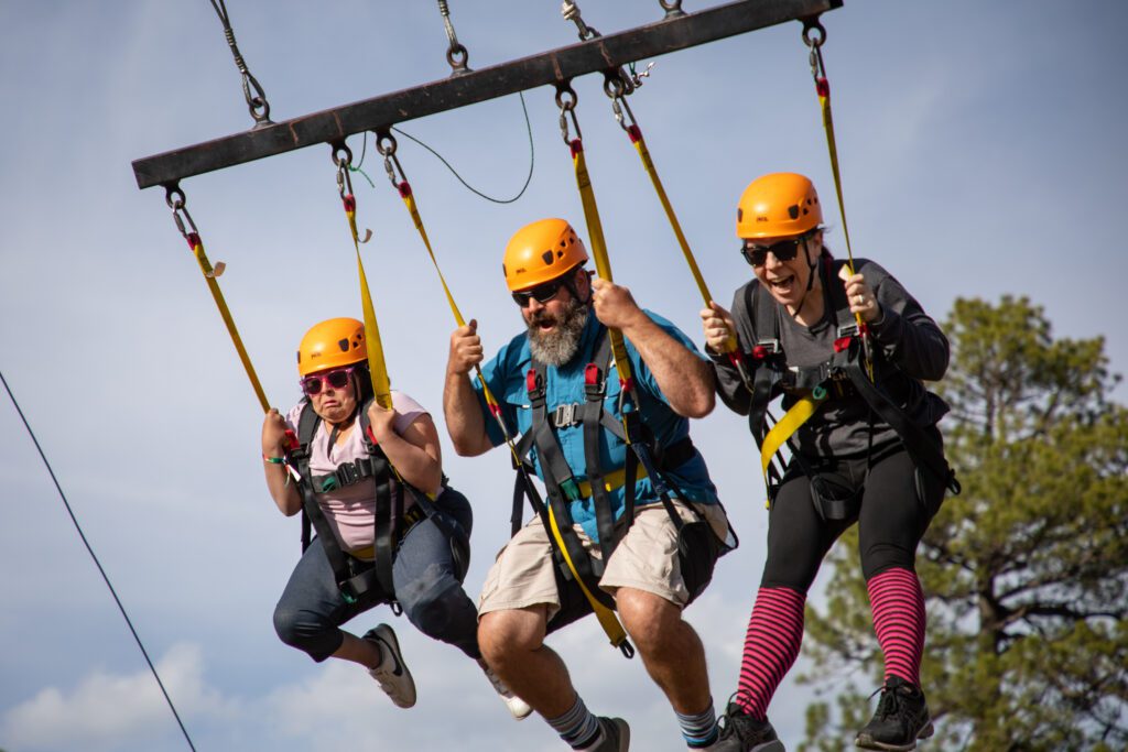 A camper and two staff members swing on the giant swing.