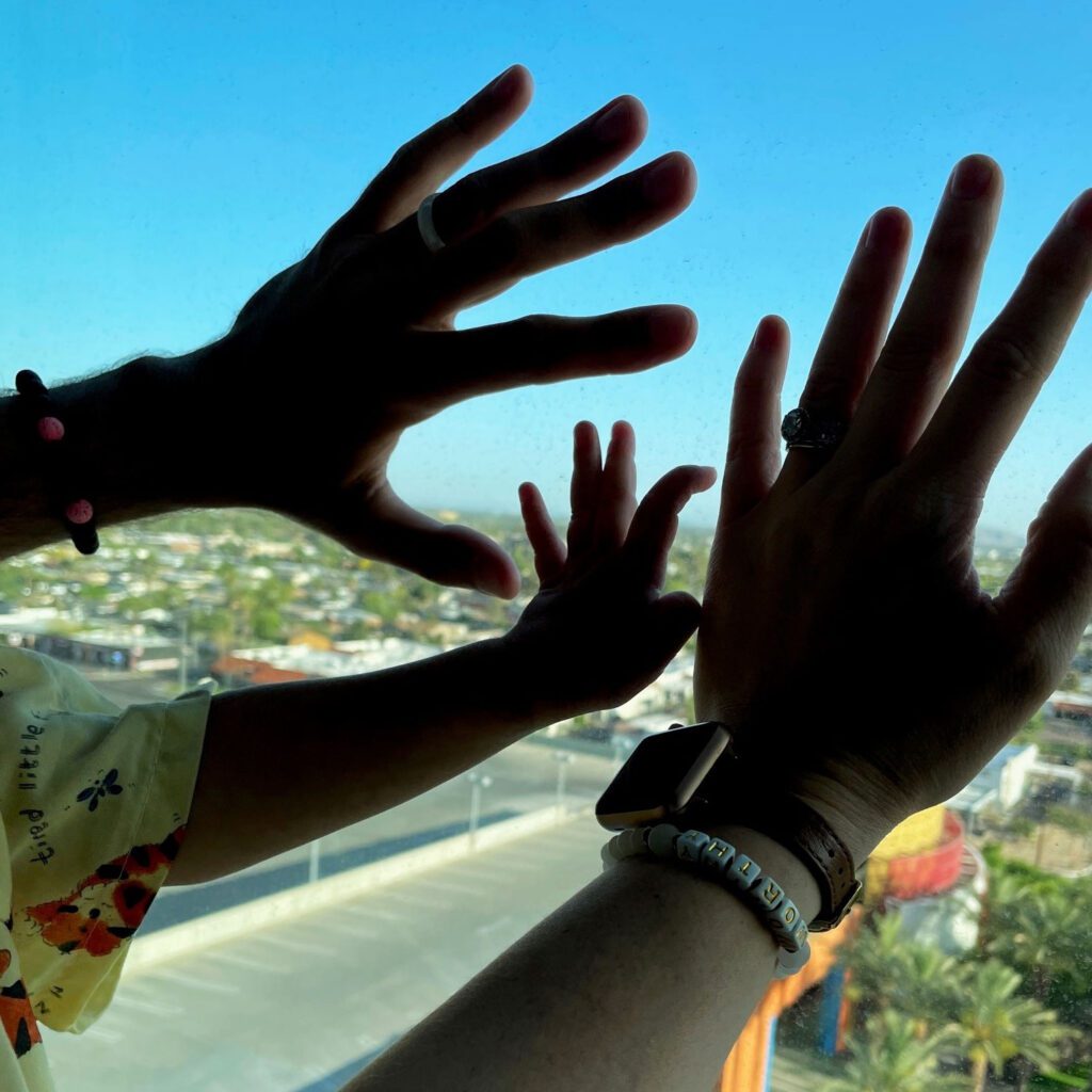 Nash and his mom and dad's hands pressed against the hospital window