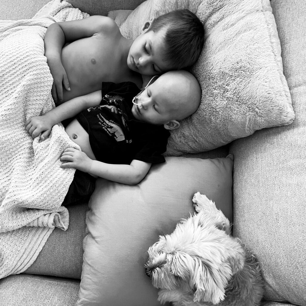 Nash at home lying in bed with his older brother
