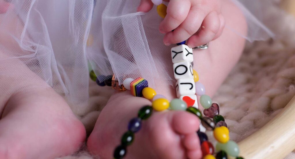 A close-up image of the beads on her beads of courage necklace. The beads read "Joy"