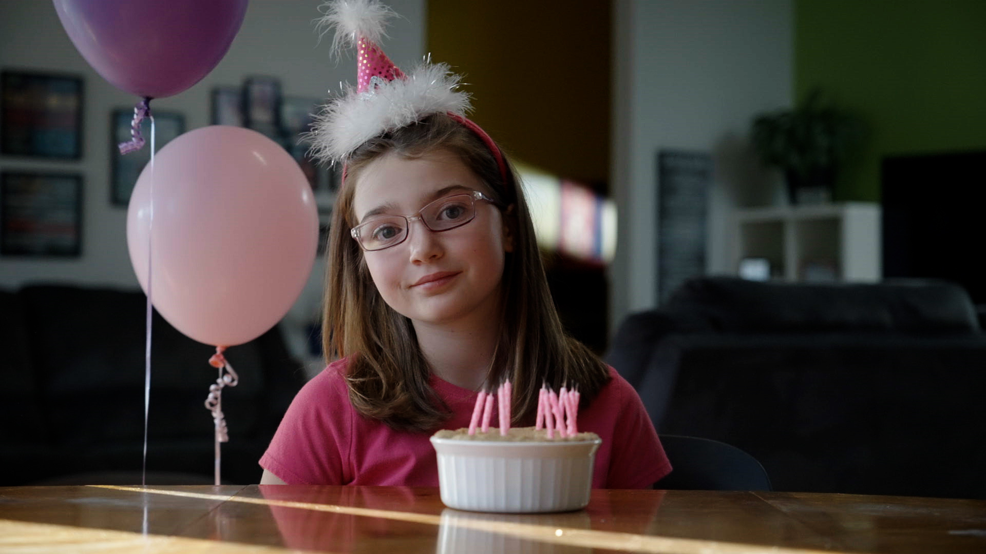 Ellie sits at her kitchen table after her family sang the "Happy Birthday" song to her. Her cake is in front of her.