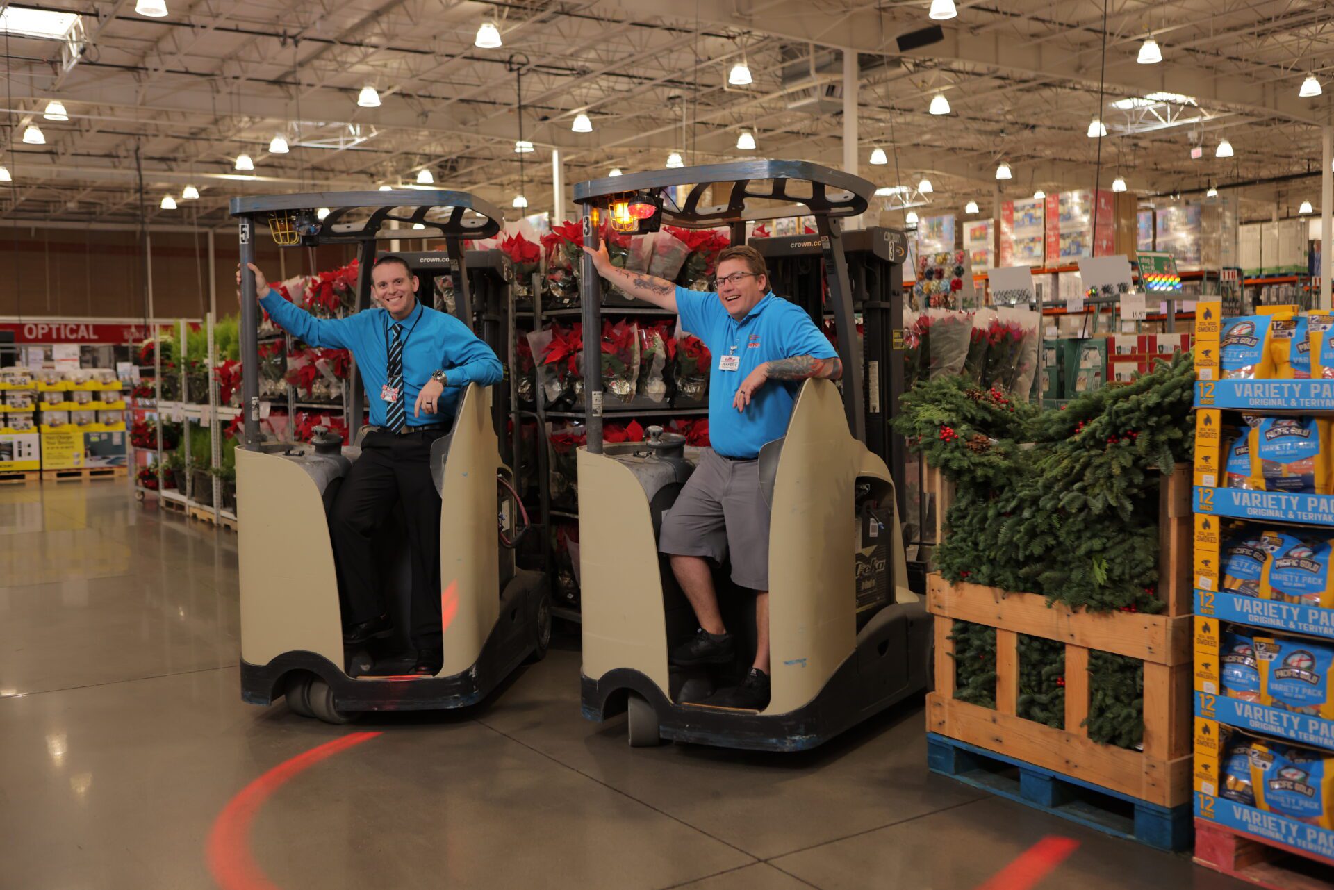 Billy Loss and Jeff Tilghman pose for a photo while standing inside Costco's forklifts. 