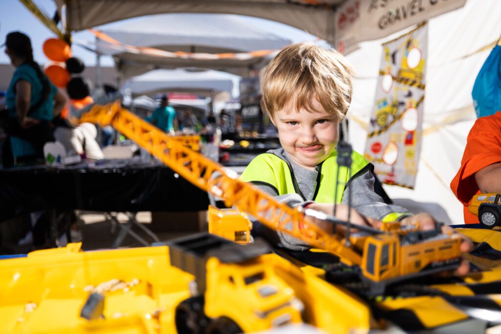 A young boy plays with a toy construction crane at the Big Dig for Kids event.