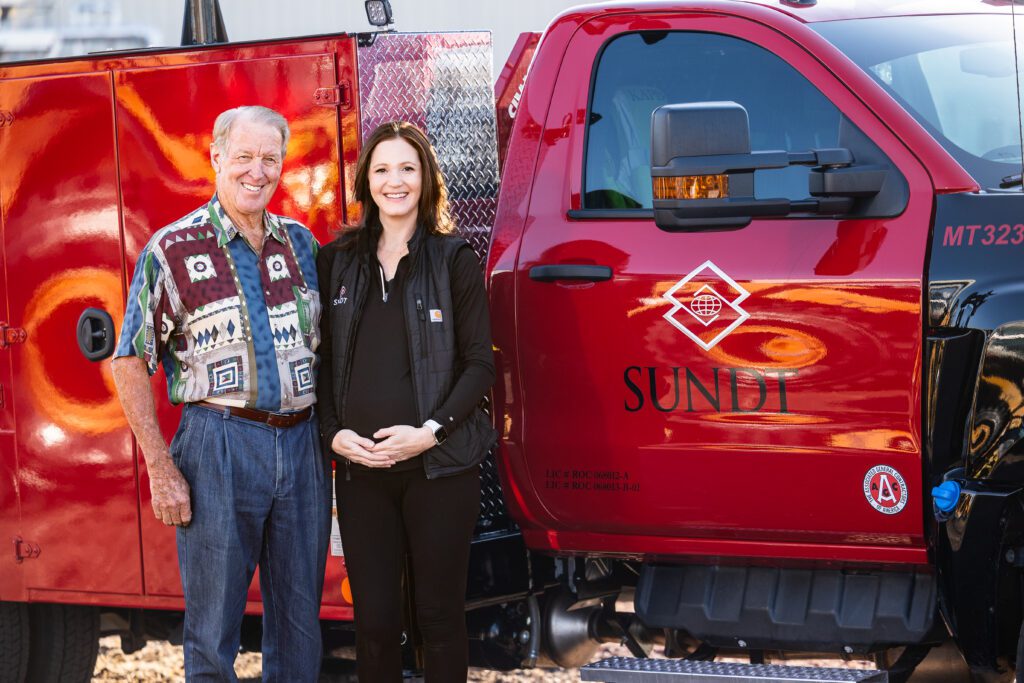 Dave Crawford and Sarah Owen pose for a photo in front of a Sundt truck.