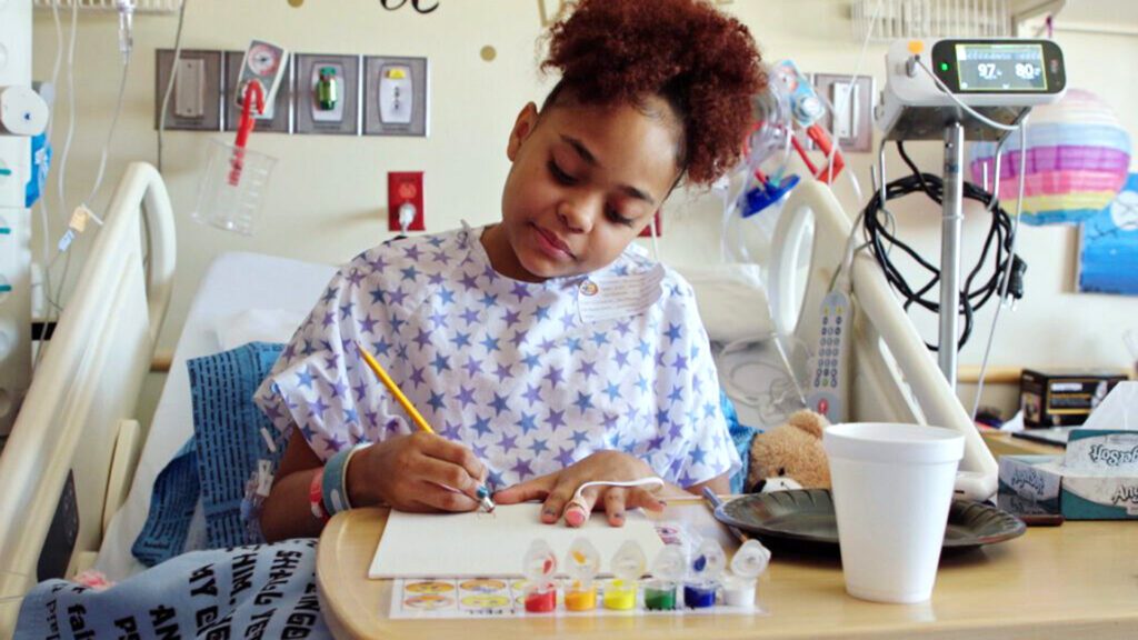A patient does artwork in her hospital bed at Phoenix Children's