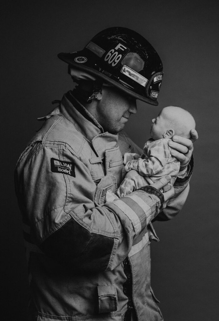 Rockwell's dad Ty is a firefighter. He holds Rockwell in this photo while dressed in his firefighter gear.