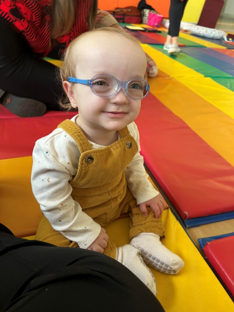 Rockwell smiles for the camera while at physical therapy. He wears blue glasses and overalls.