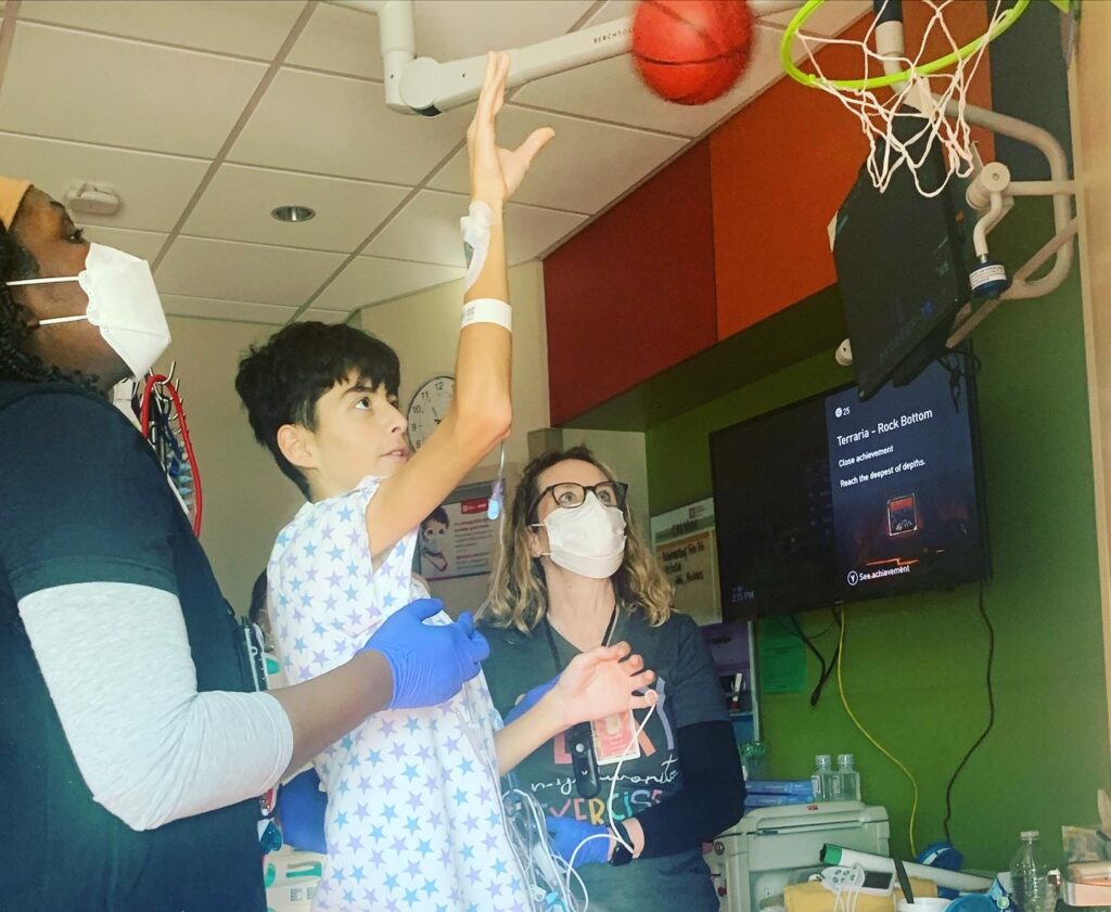 Calvin shoots a basketball into a plastic hoop in his hospital room at Phoenix Children's.