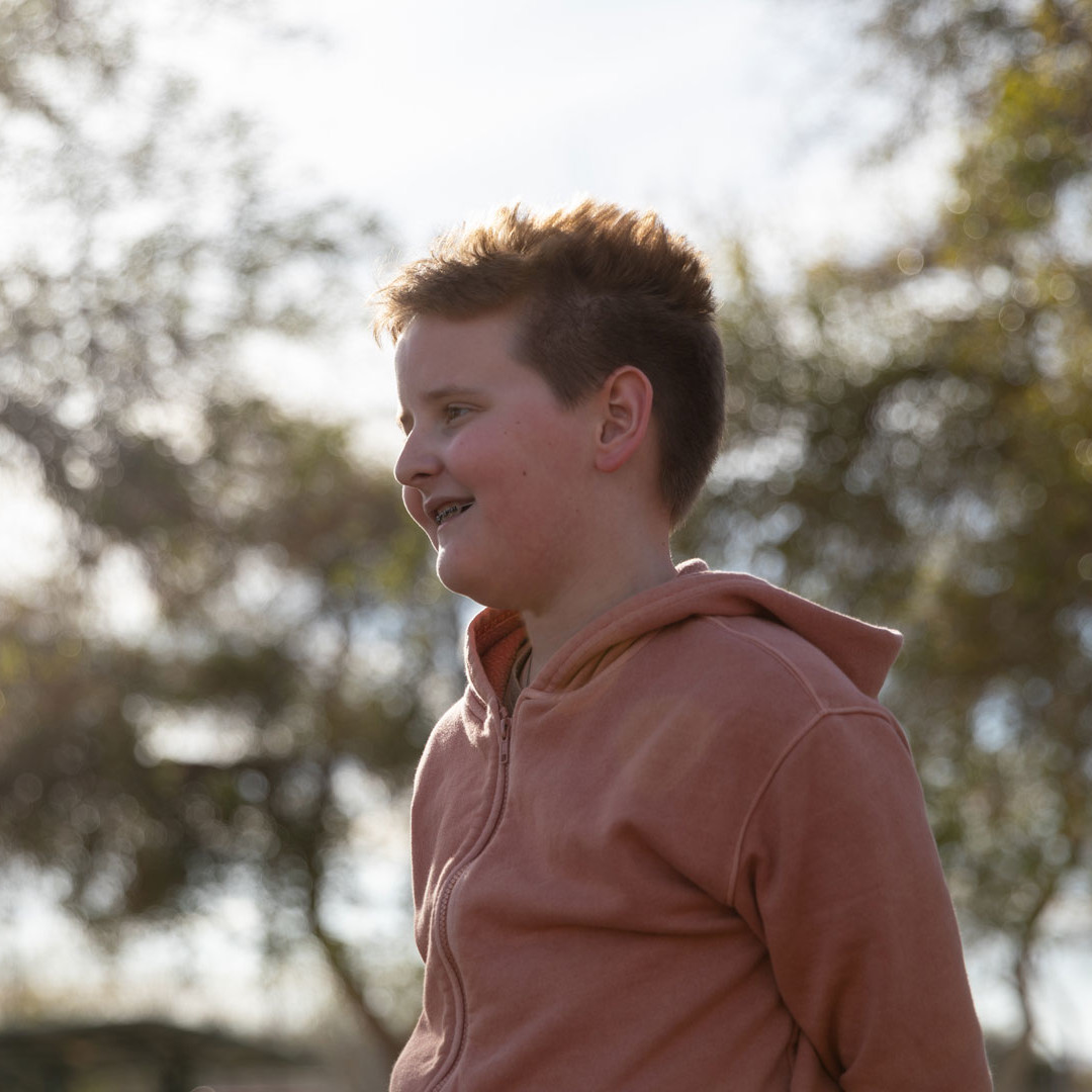 Oliver, a brave young boy who has faced mental health challenges, smiles looking left off camera.