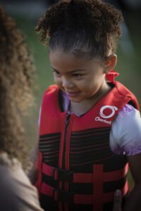 A closeup of a child wearing a red life jacket.