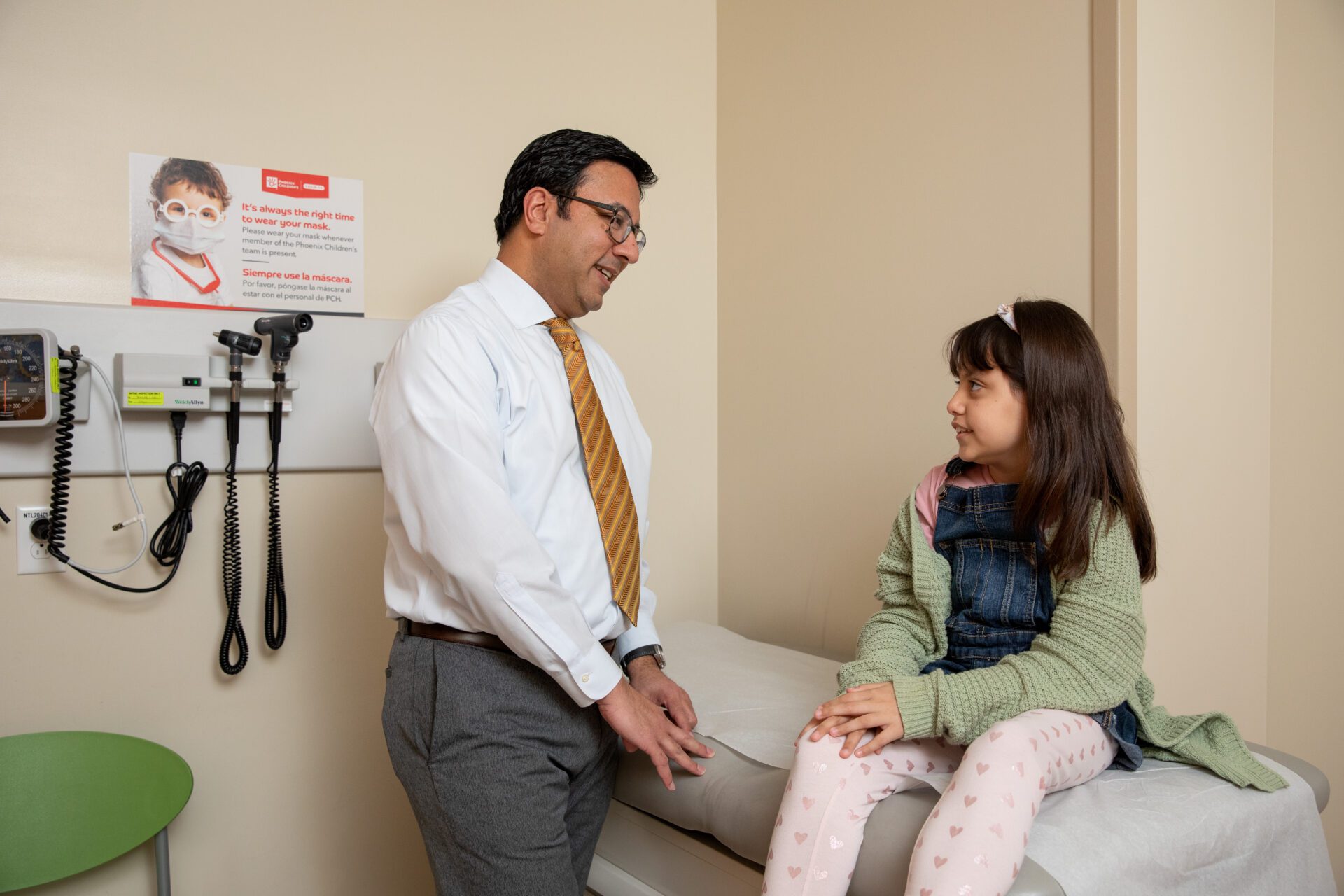 A physician talks with a patient in an exam room.