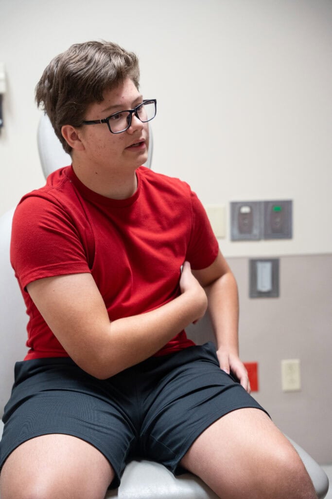 Dalton sits on an exam table in the interventional pain suite. 