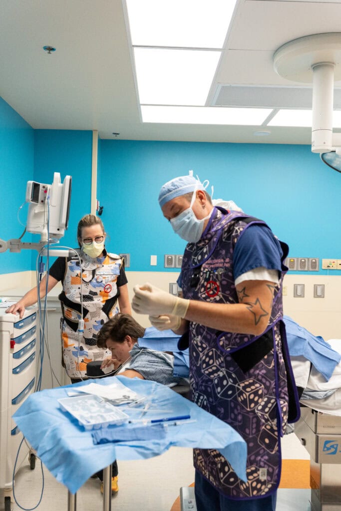 Dr.  Sean Gamble and a nurse prepare to give Dalton an epidural steroid injection in Phoenix Children's interventional pain suite. 