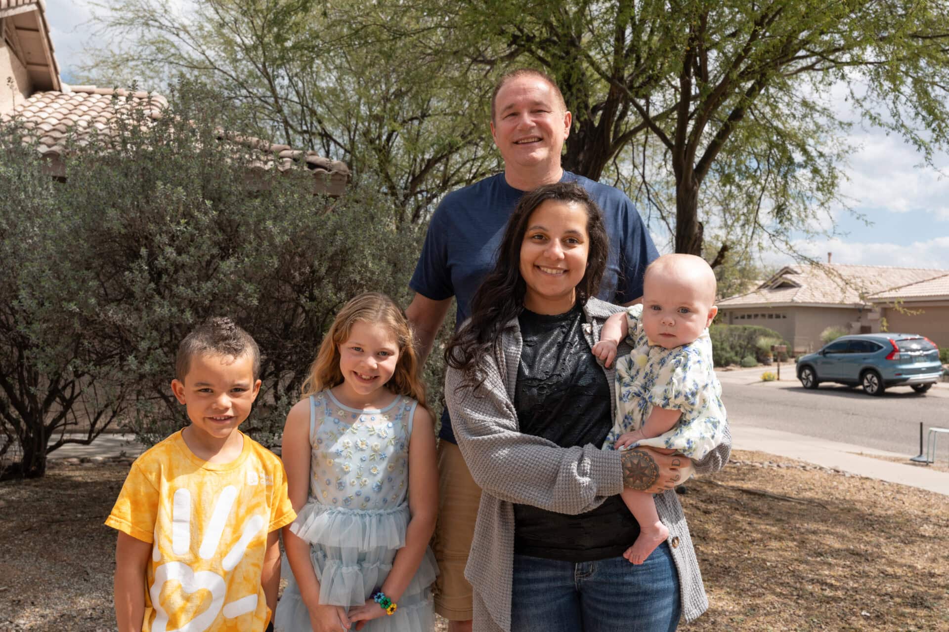 A family poses for a photo in their backyard.