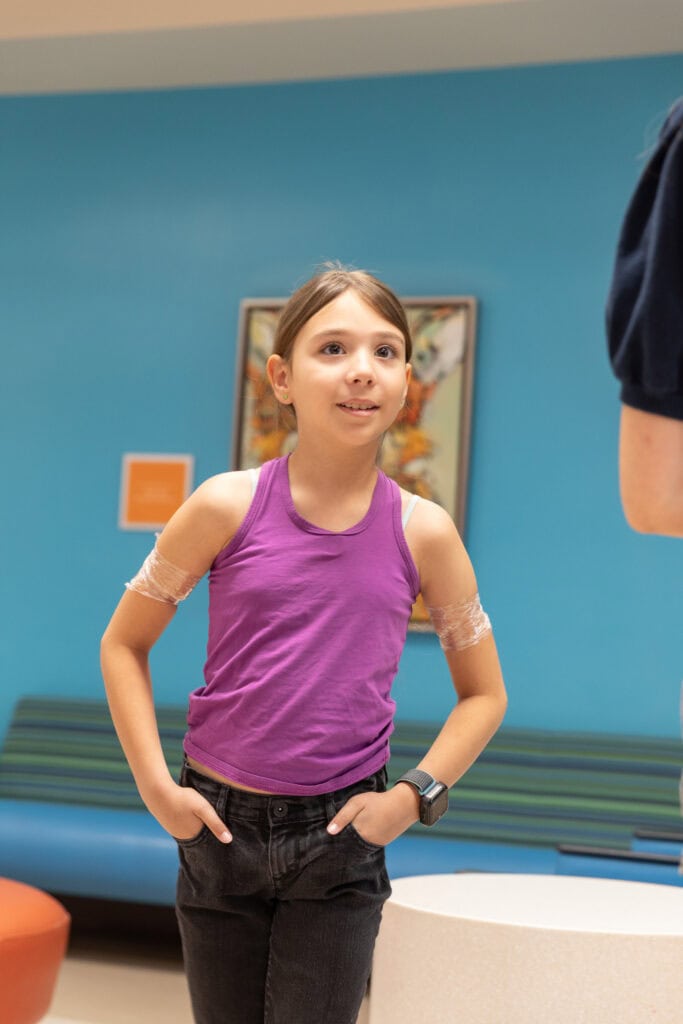 A young girl walks through a hospital corridor. 