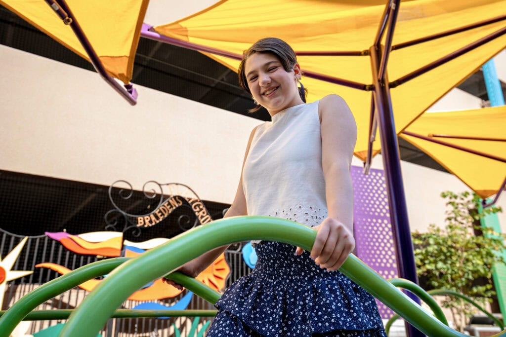 A girl stands on colorful playground equipment.