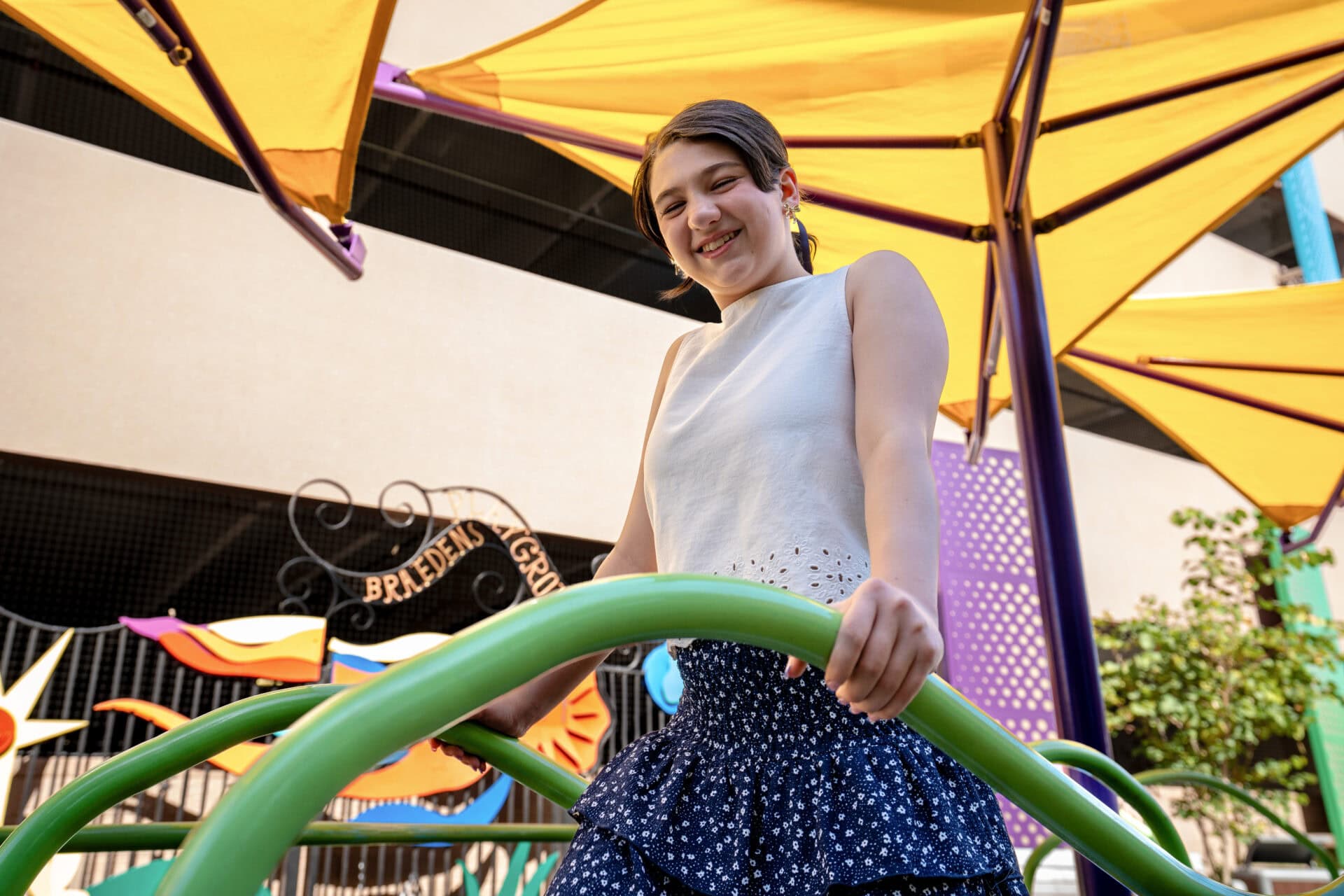 A girl stands on colorful playground equipment.